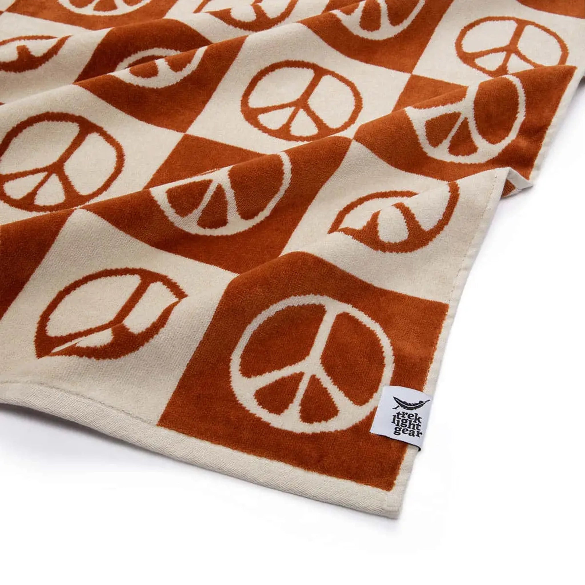 A brown/rust and cream checkered beach and bath towel that has a coordinating peace sign design in each square.