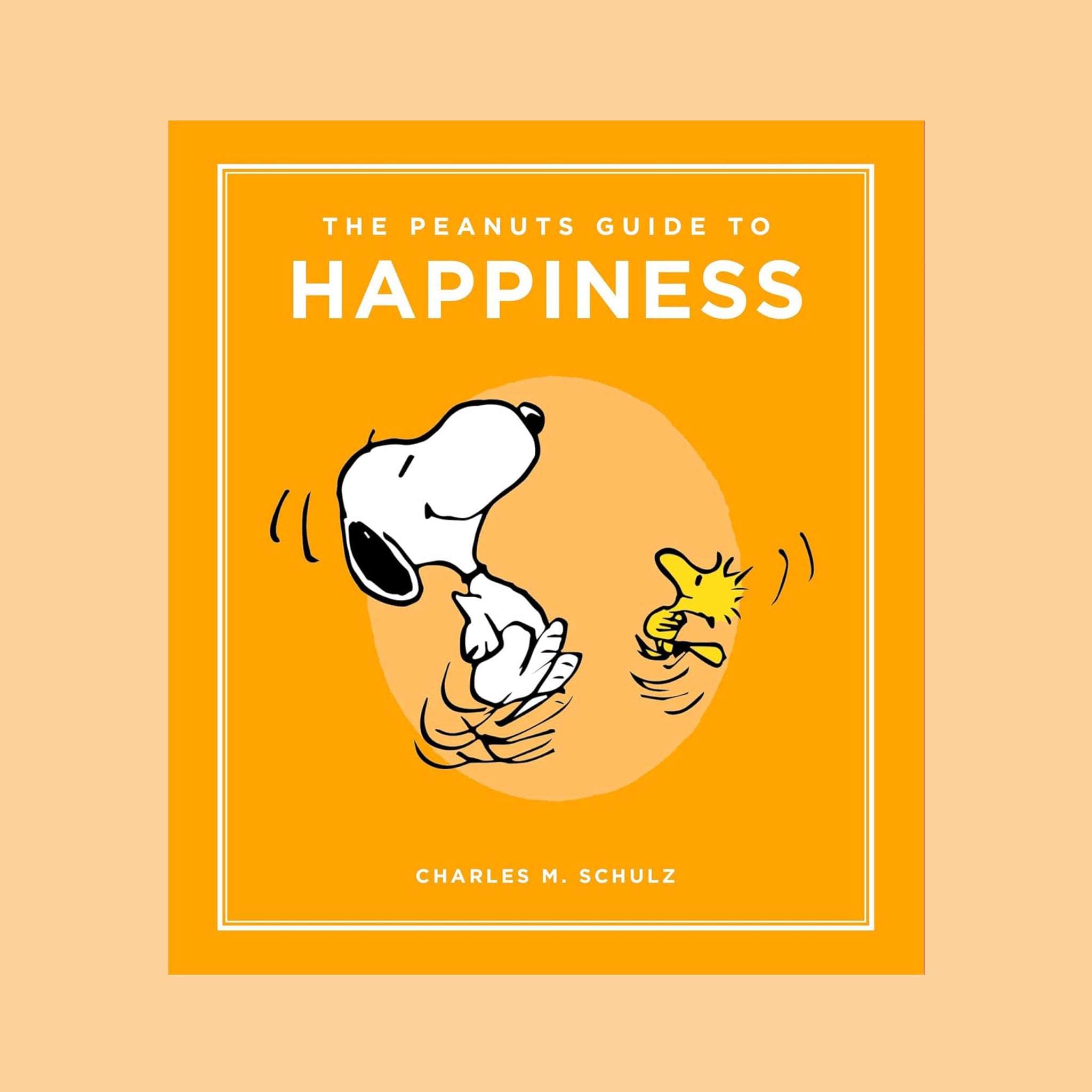 "The Peanuts Guide To Happiness Charles M. Schulz" with a illustration of Snoopy. 