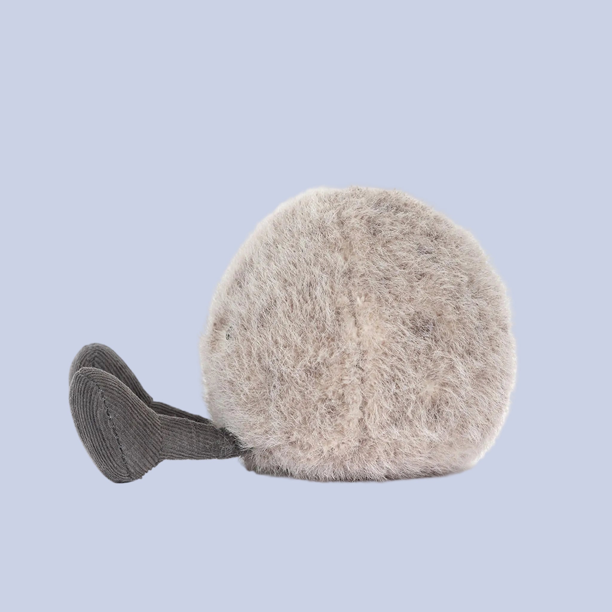 Plush toy resembling a round pebble with a smiling face on a blue background