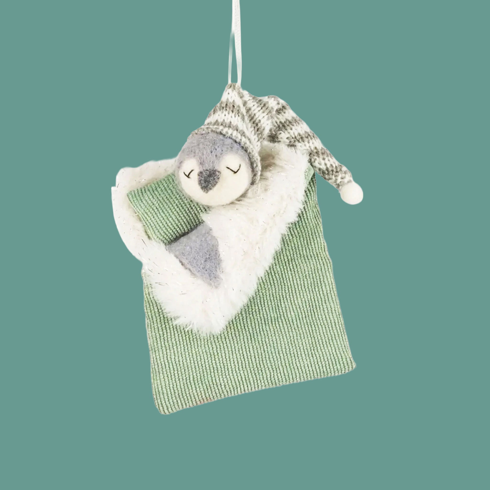 A penguin shaped ornament sleeping in a sleeping bag. 
