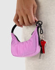 A small crescent bag charm in a pink shade with black straps and zipper. 