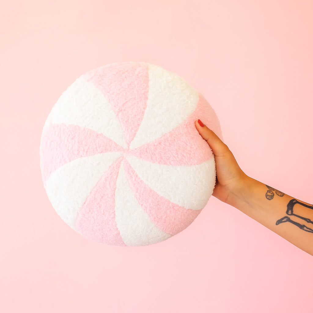 A round pink and white peppermint swirl candy shaped throw pillow. 