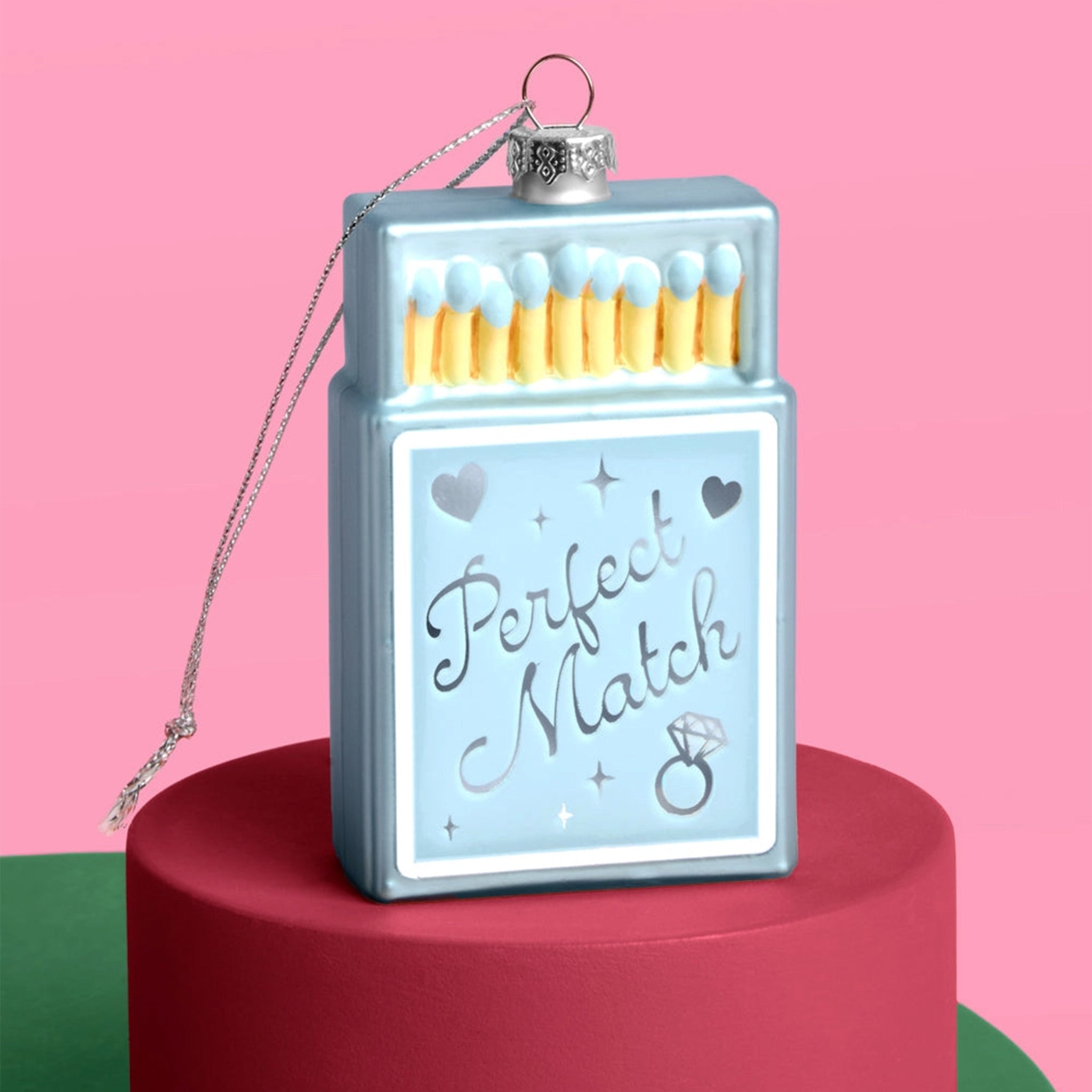 A blue matchbox shaped ornament that reads, "Perfect Match". 