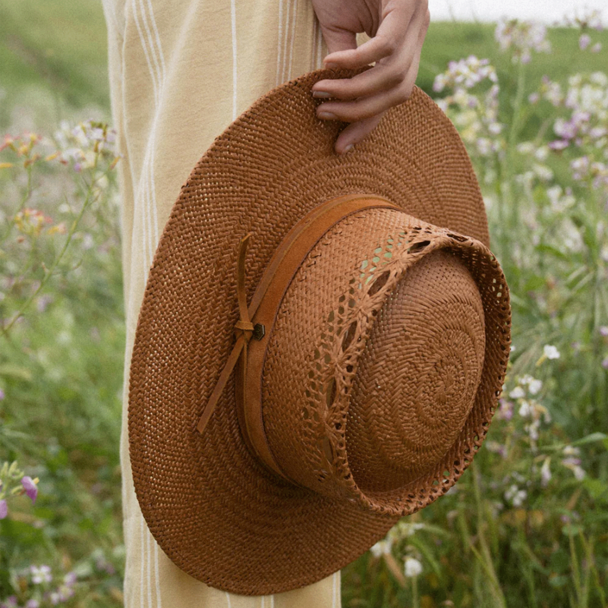 A light brown woven sun hat with details on the crown of the hat and a strap around the base. 