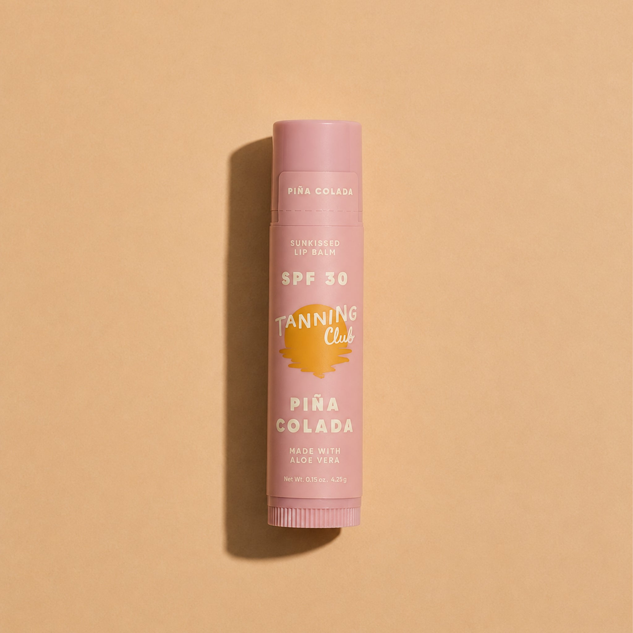 Pink lip balm with 'Pina Colada' flavor on a beige background