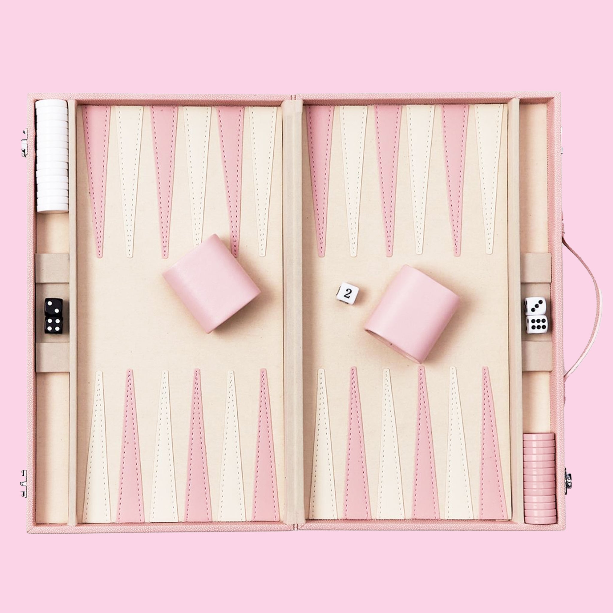 On a pink background is a pink and tan backgammon board game set. 