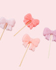 A set of four bow shaped birthday candles. 