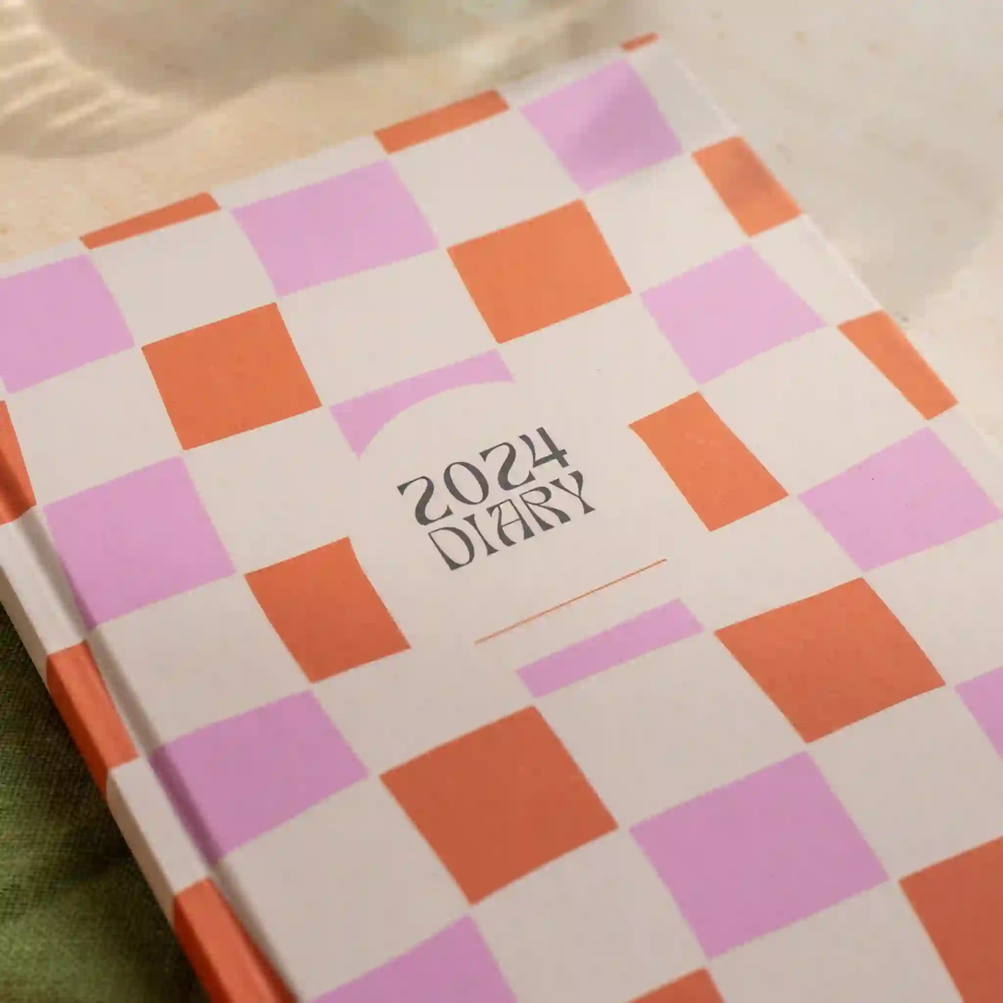 A pink and orange hardback diary with black text in the center that reads, "2024 Diary". 