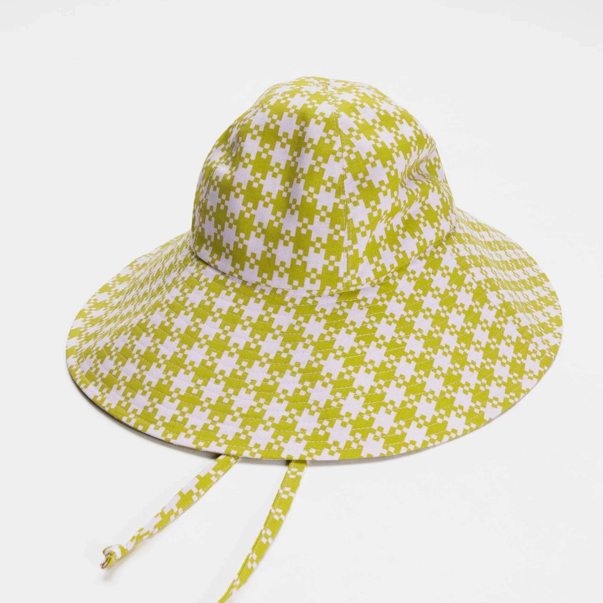 On a white background is a pink and green flexible sun hat with to straps for securing around the neck.