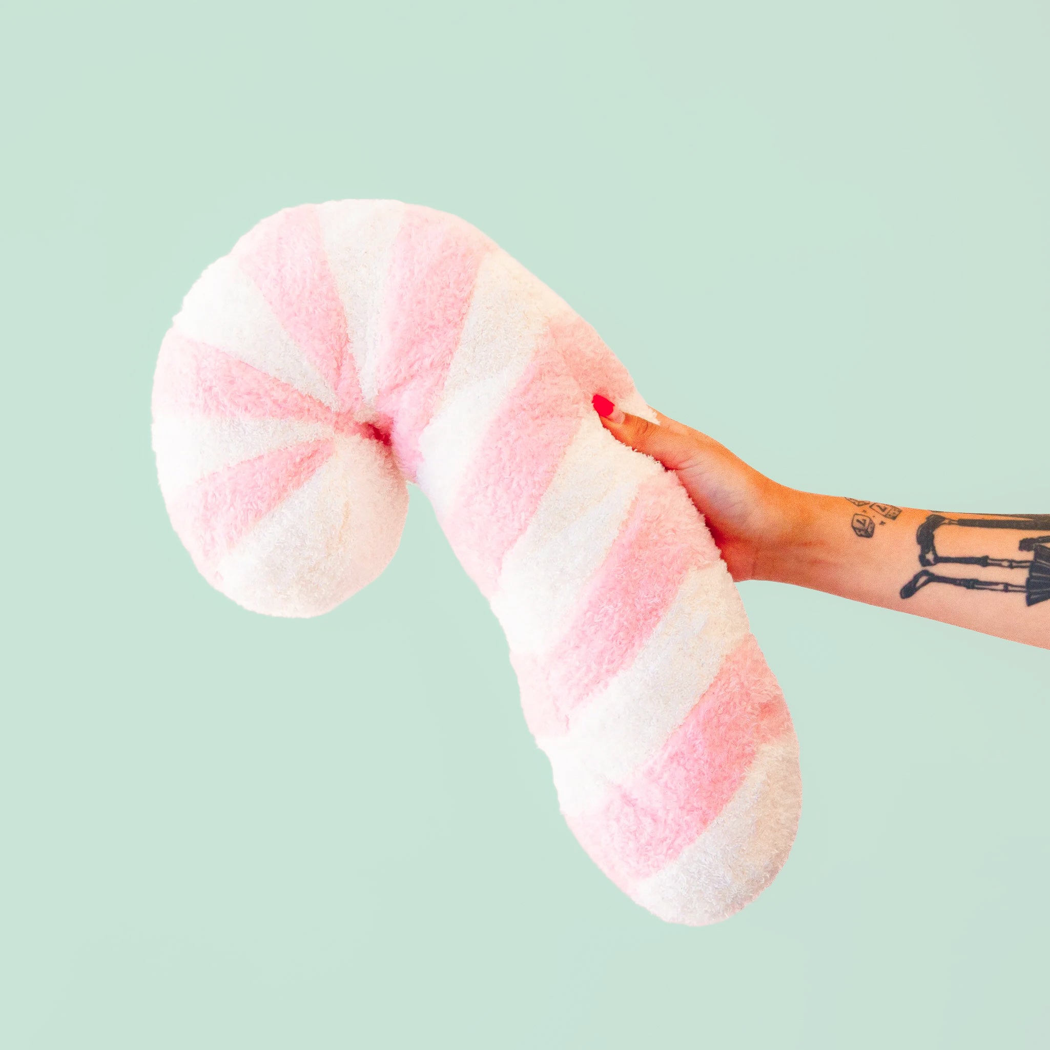 A light pink and white striped candy cane shaped pillow. 