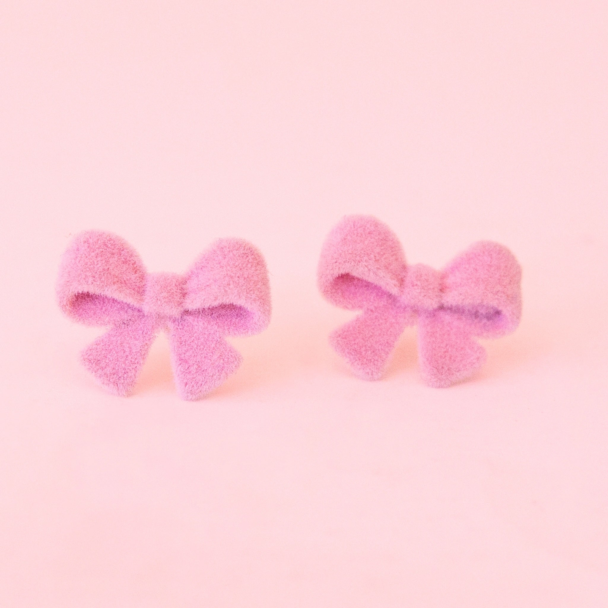 A pair of flocked pink bow shaped earrings. 