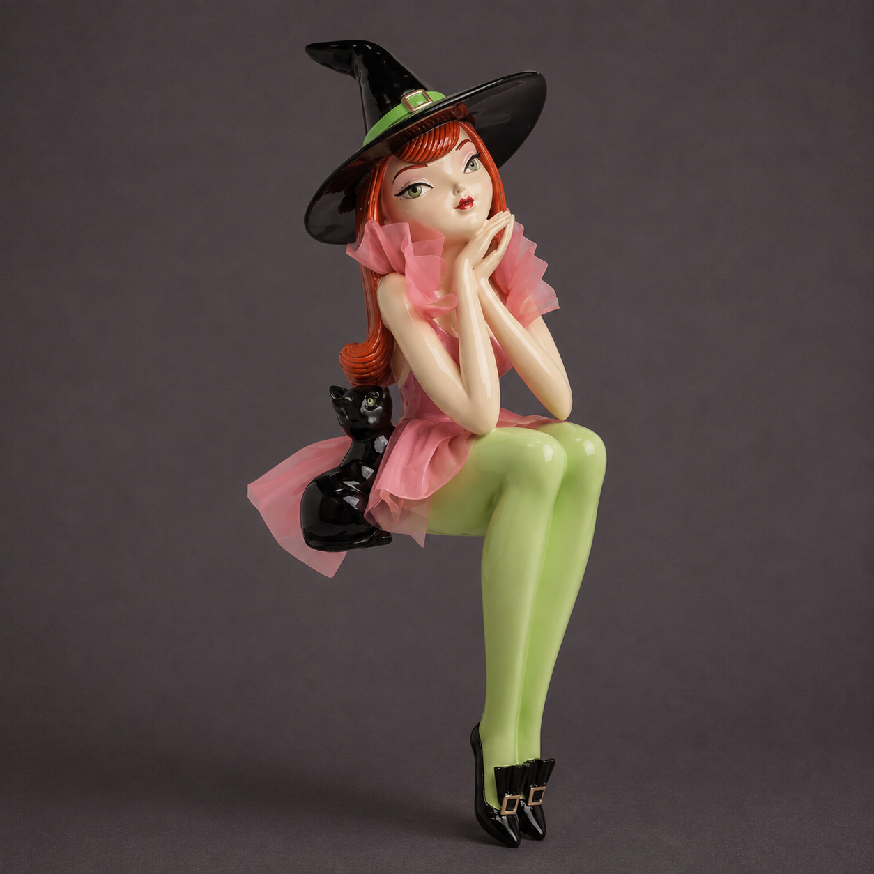A green and pink witch shaped figurine made for sitting on the edge of shelves and mantles 