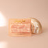 Pink pearl detailed hair barrettes on a coral colored piece of paper and a shell behind.