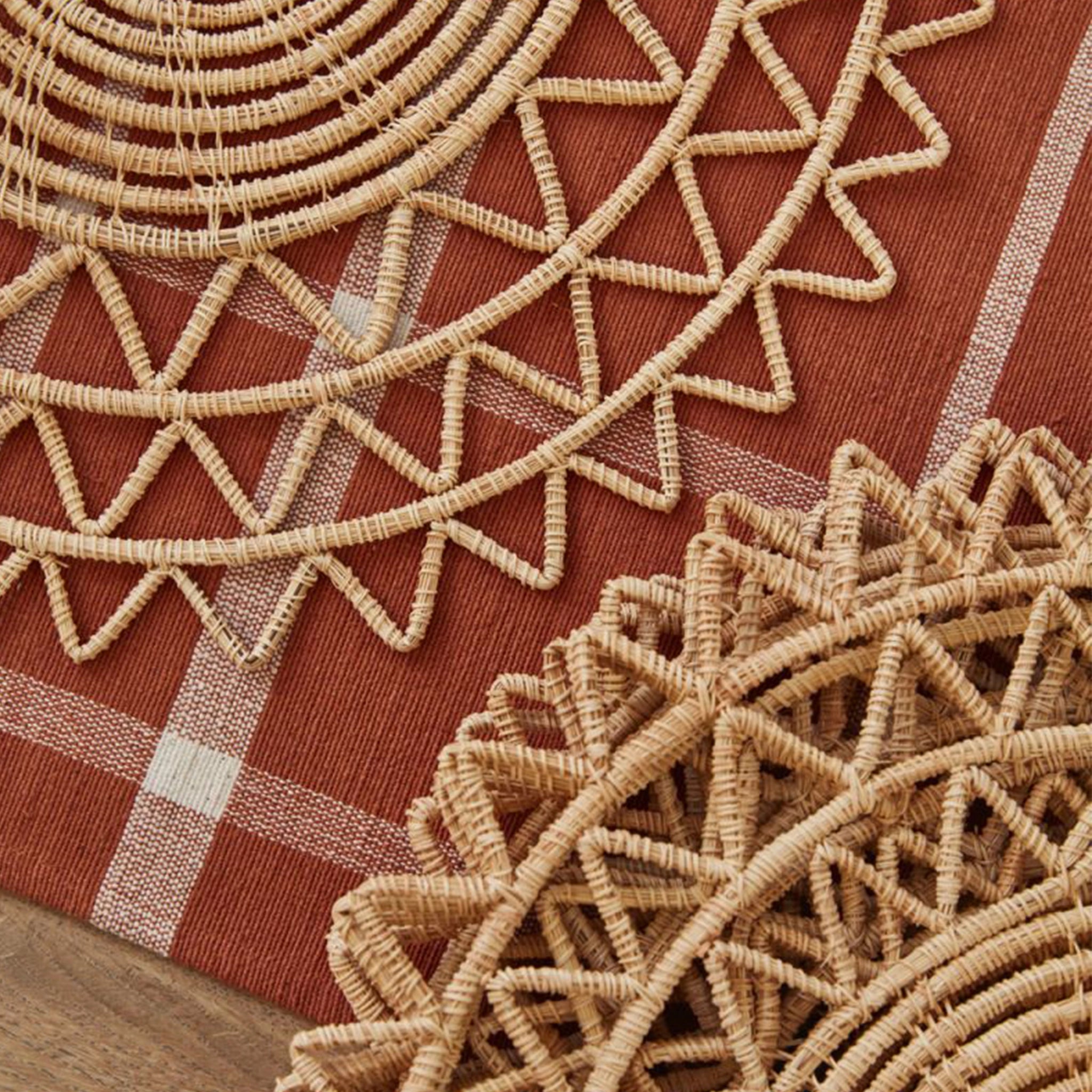On a rust colored background is a wicker sun shaped placemat.