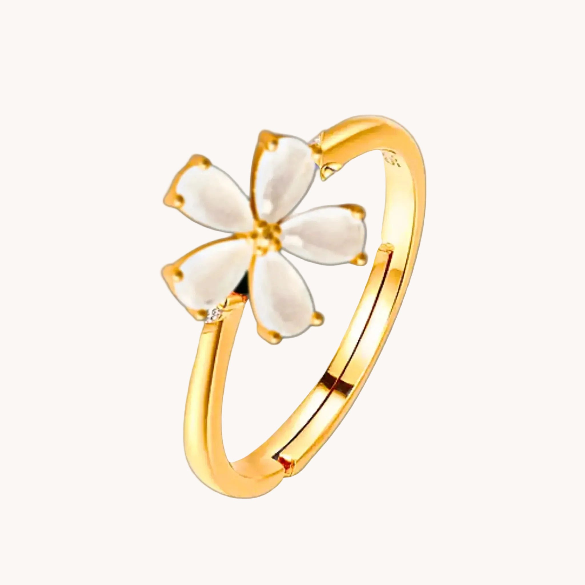 Gold ring with a white flower-shaped design on a white background