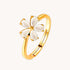 Gold ring with a white flower-shaped design on a white background