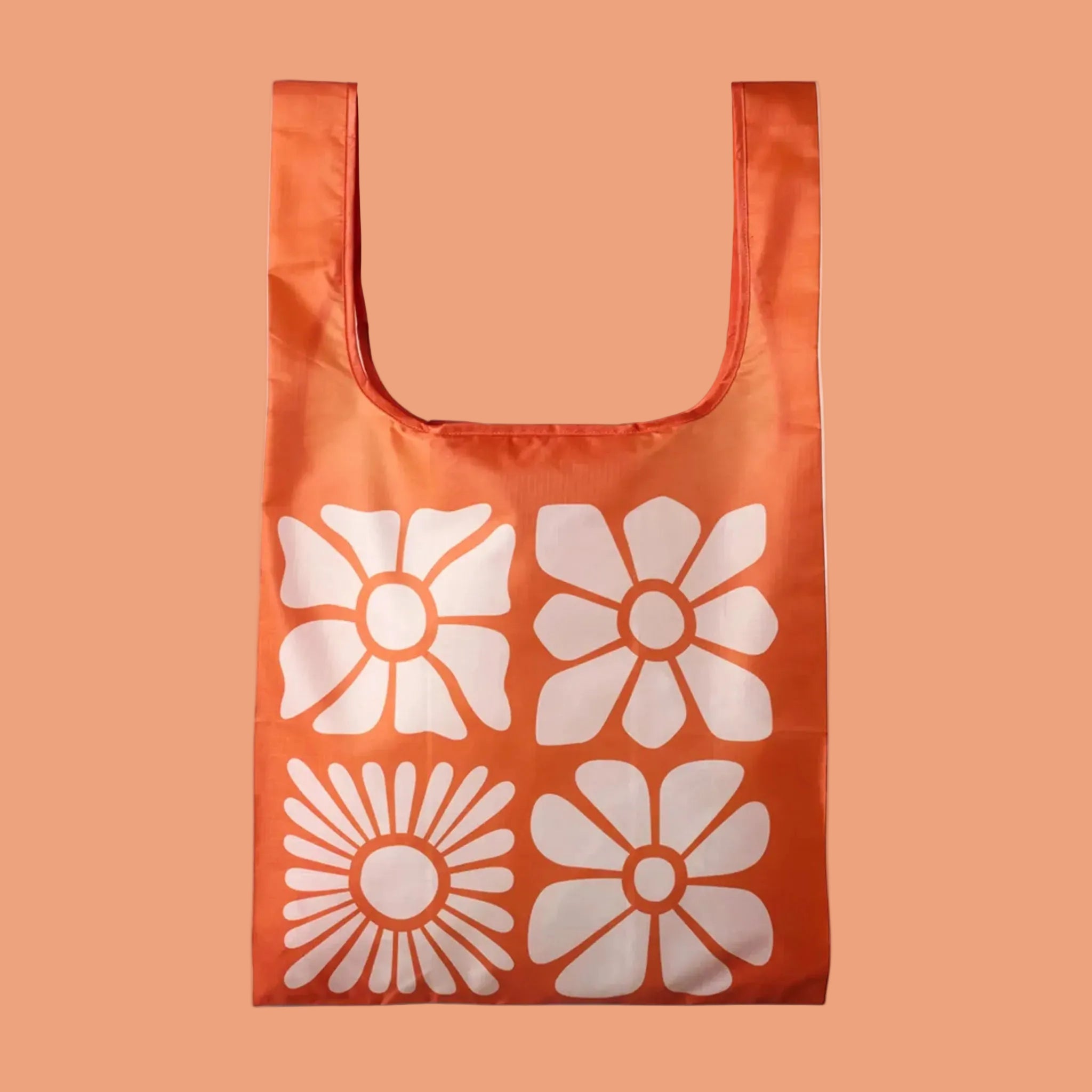 An orange foldable tote bag with a neutral large floral pattern. 