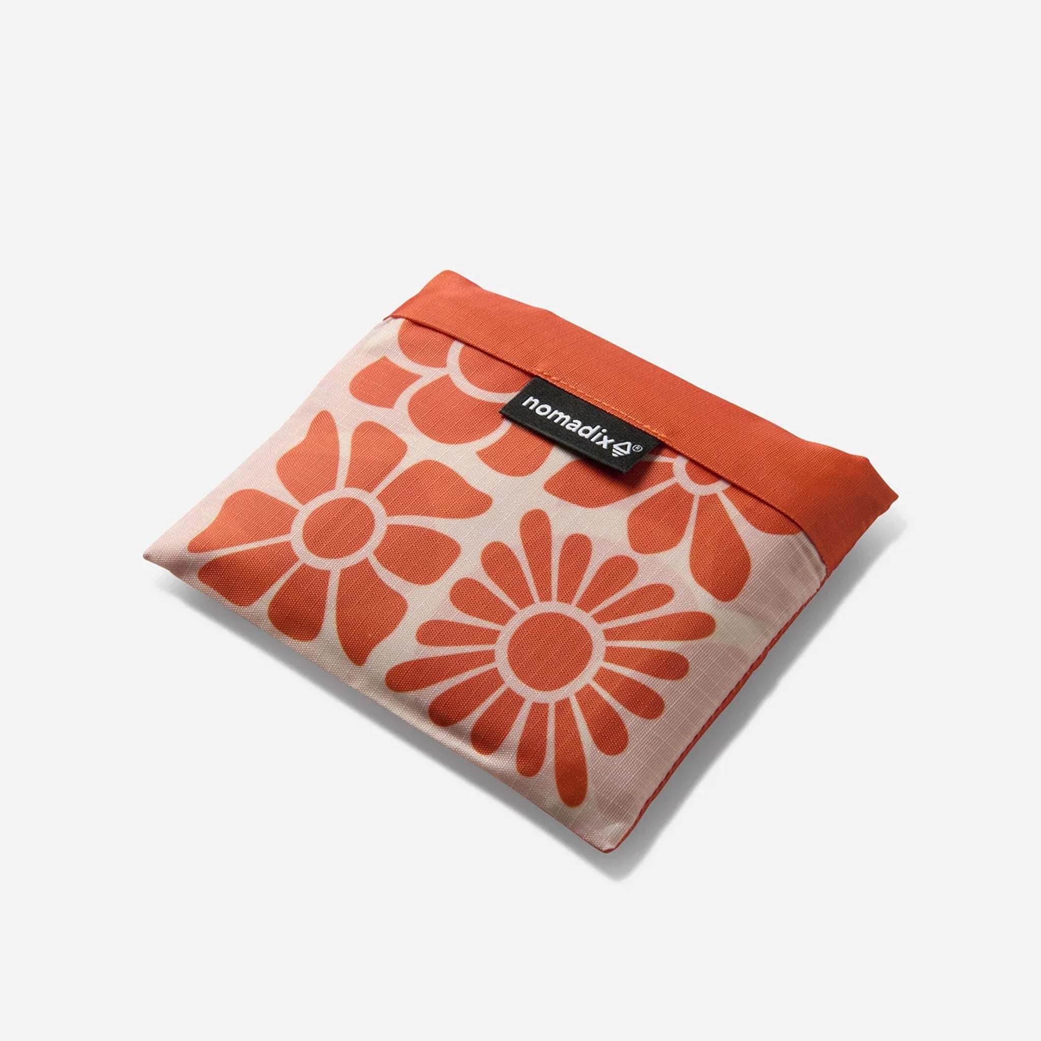 An orange foldable tote bag with a neutral large floral pattern. 