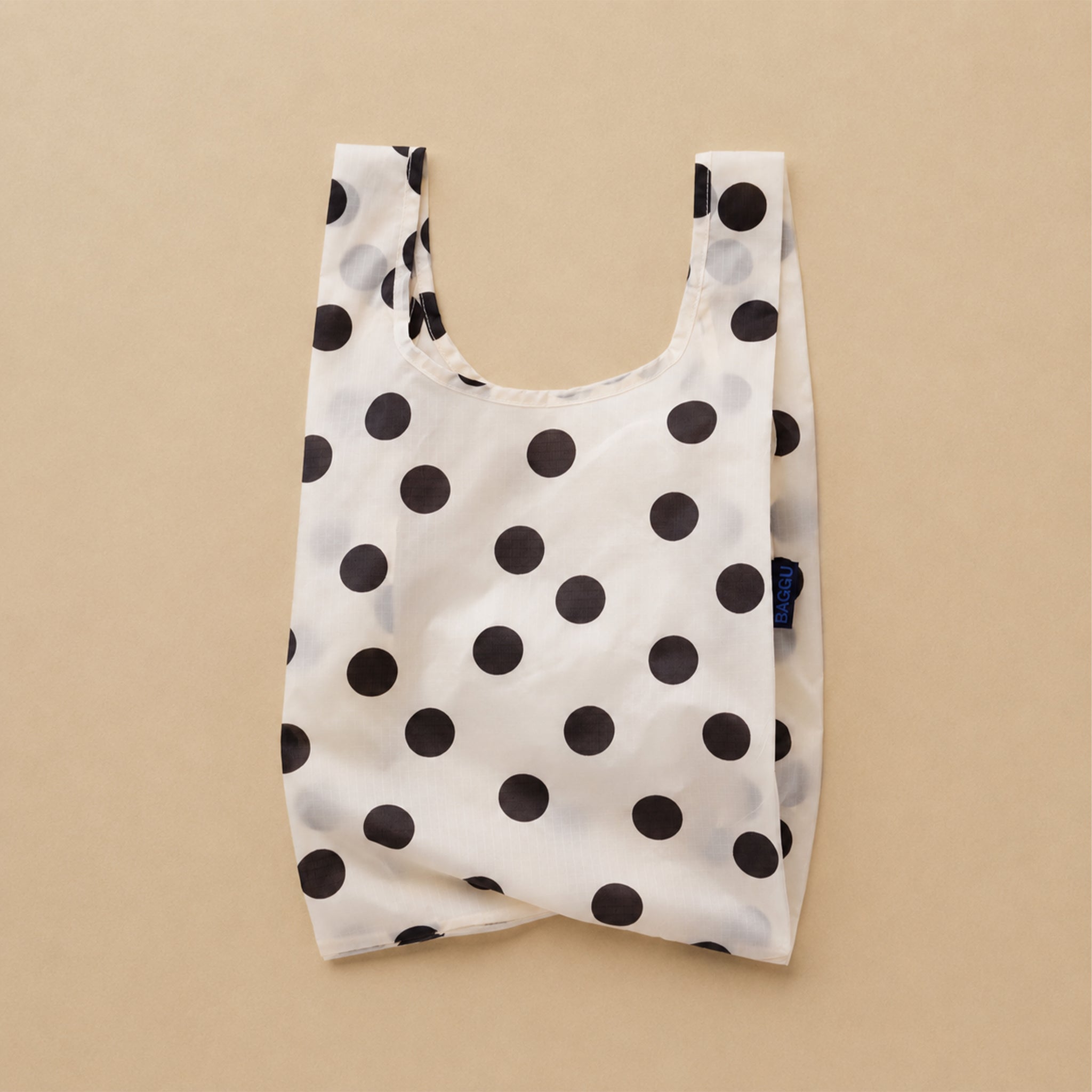 A cream and black polka dot nylon tote bag.