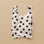 A cream and black polka dot nylon tote bag.
