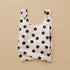 A cream and black polka dot nylon tote bag.