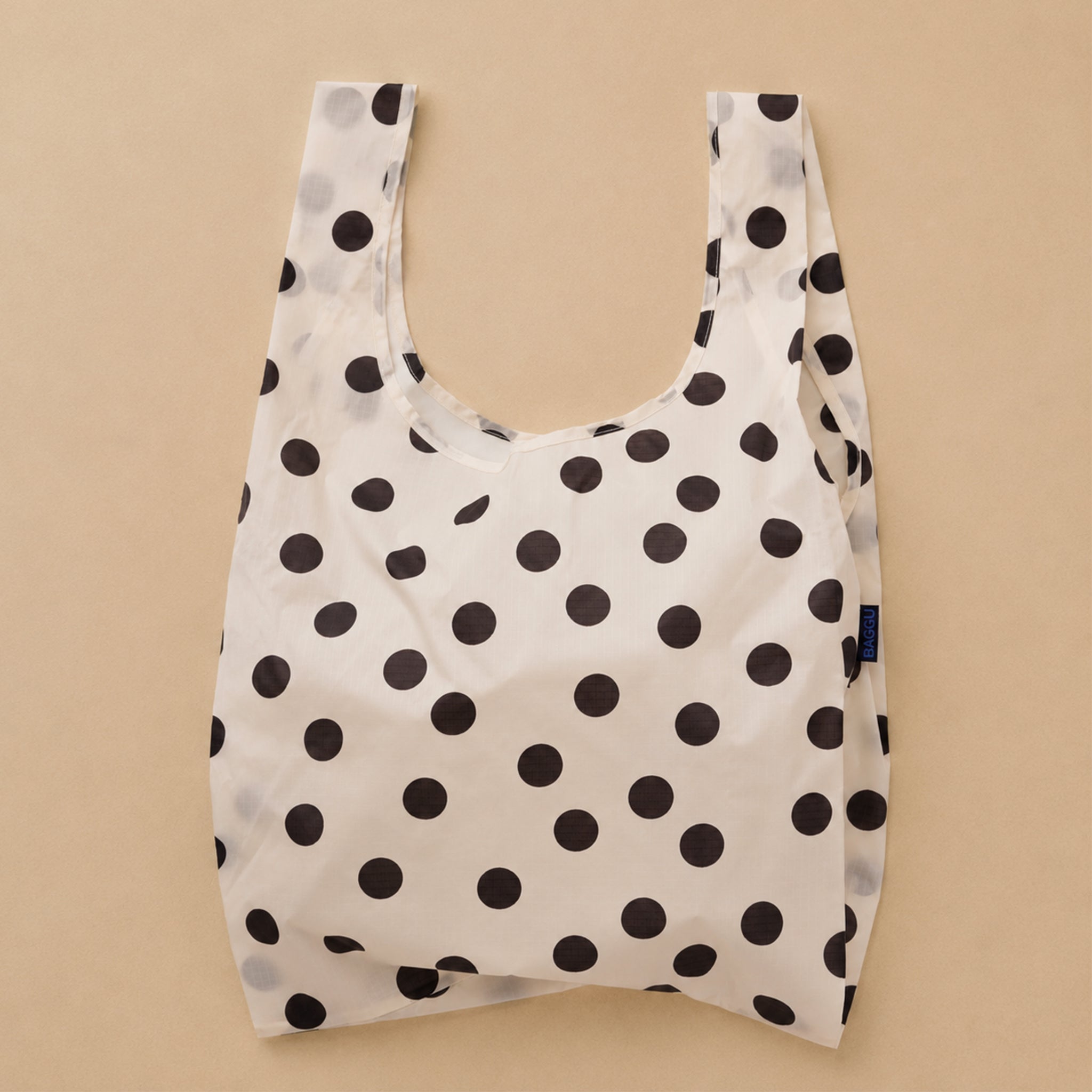 A cream and black polka dot nylon tote bag.