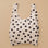 A cream and black polka dot nylon tote bag.