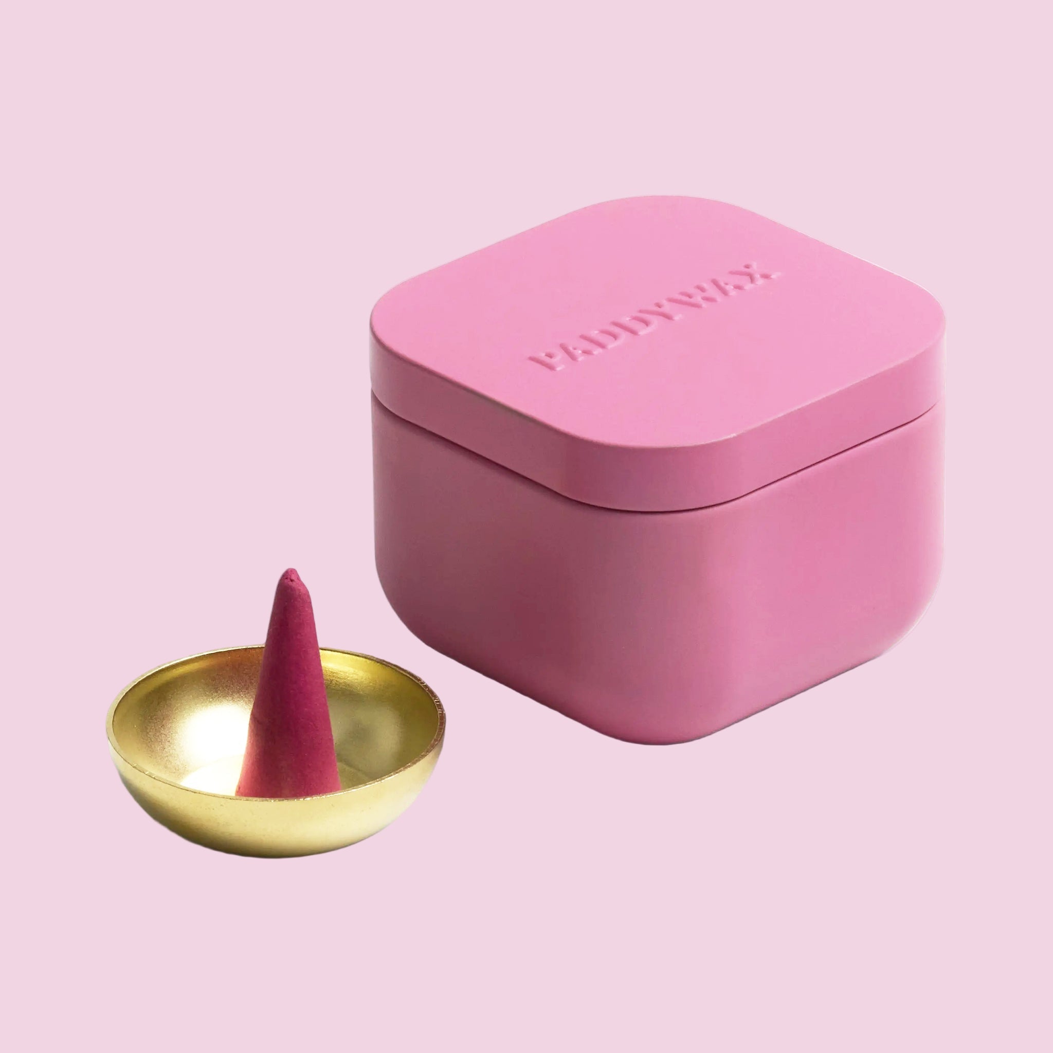 A pink box of incense cones and a gold small bowl for setting. 