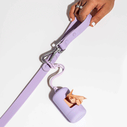 On a white background is a lavender waste bag carrier attached to a leash not included. 