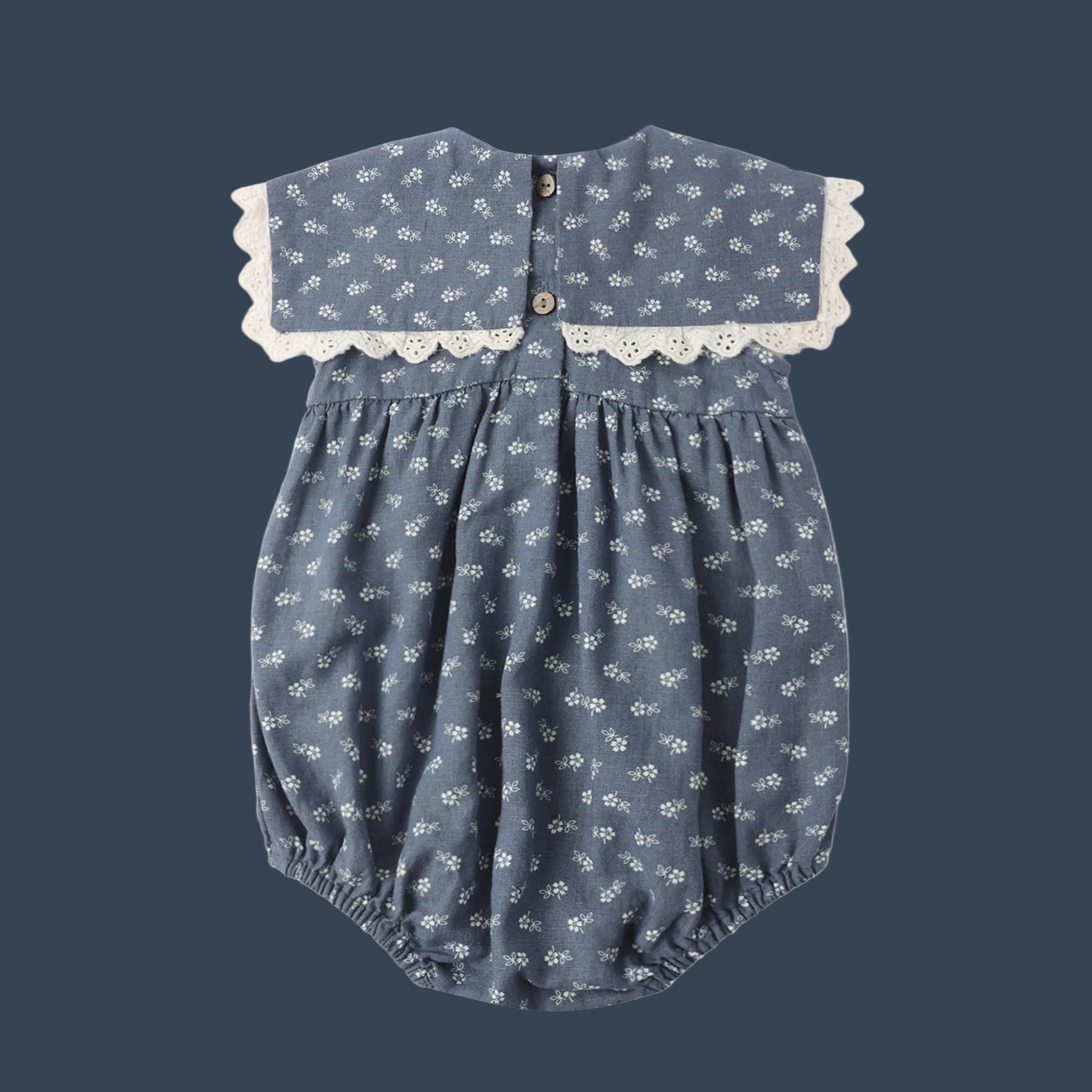 A blue and white floral romper for babies with a laced edge bib collar detail. 
