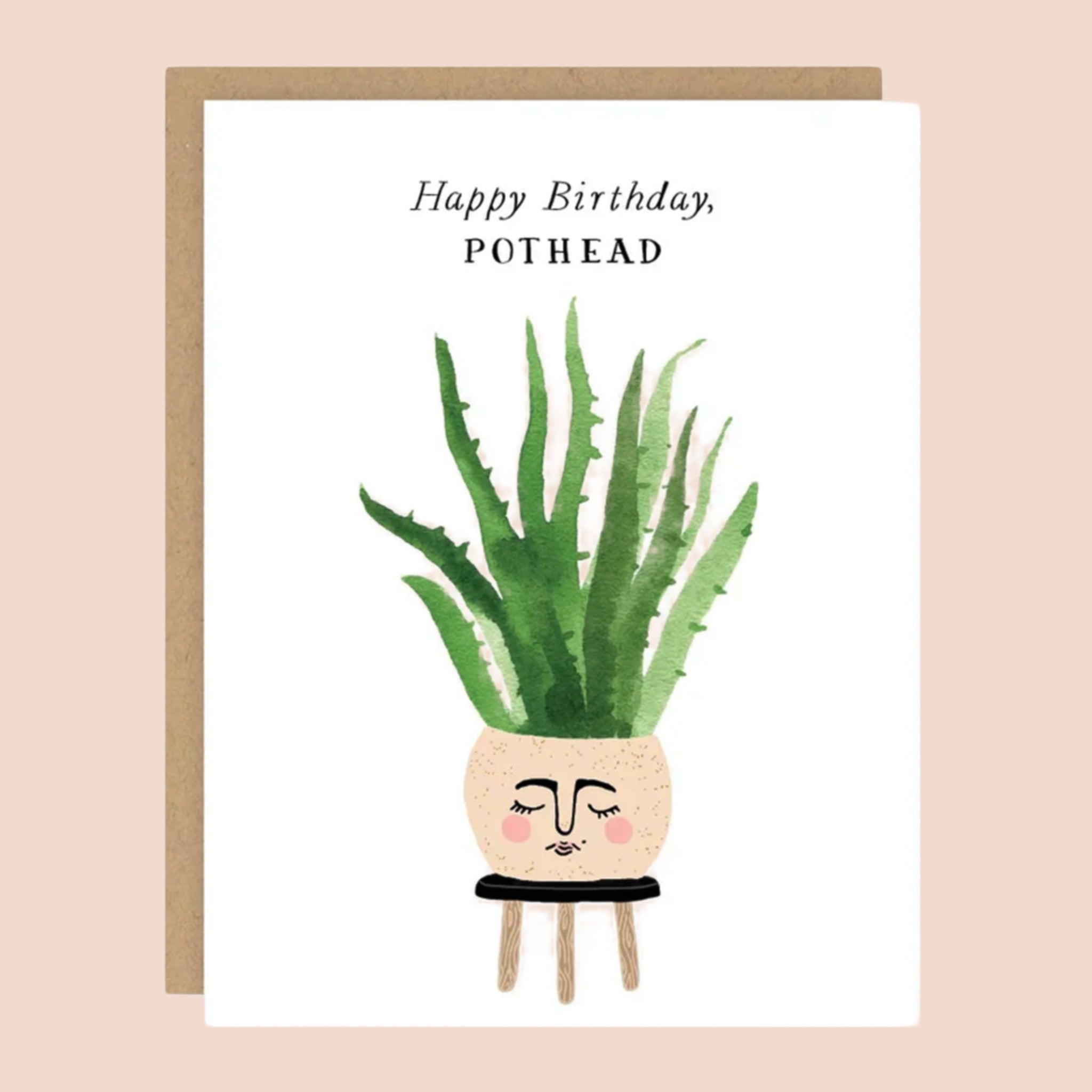 On top of a kraft envelope is a white card. In the middle of the card is a water color painting of a round tan pot sitting on top of a black stool. There is face painted on the front of the pot. Inside the pot is a tall green plant. At the top is black text that reads ‘happy birthday pothead.