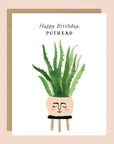 On top of a kraft envelope is a white card. In the middle of the card is a water color painting of a round tan pot sitting on top of a black stool. There is face painted on the front of the pot. Inside the pot is a tall green plant. At the top is black text that reads ‘happy birthday pothead.