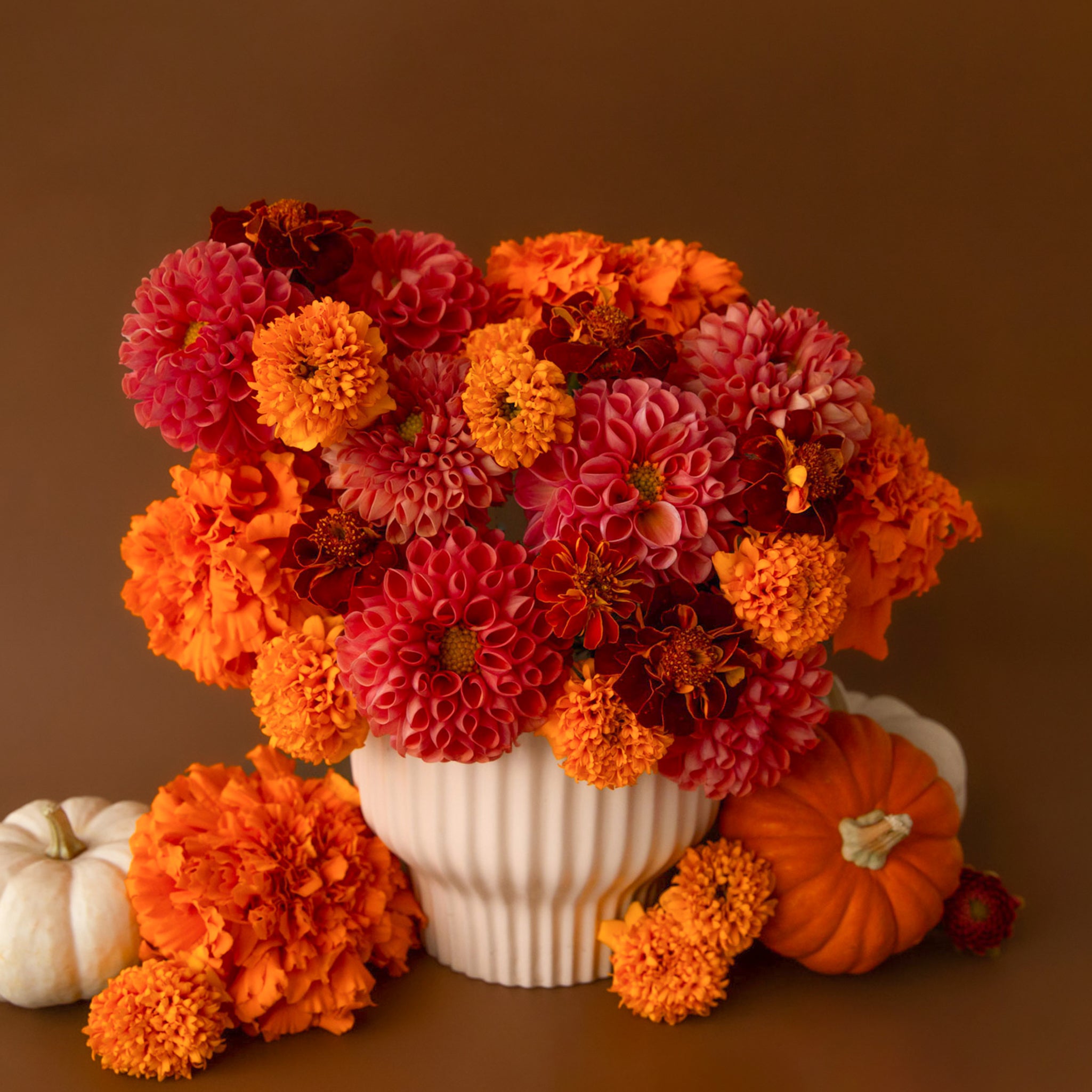 On a burnt orange background is a white ribbed pedestal planter