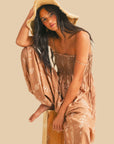 A taupe balloon leg jumpsuit with spaghetti shoulder straps and an ivory print. 