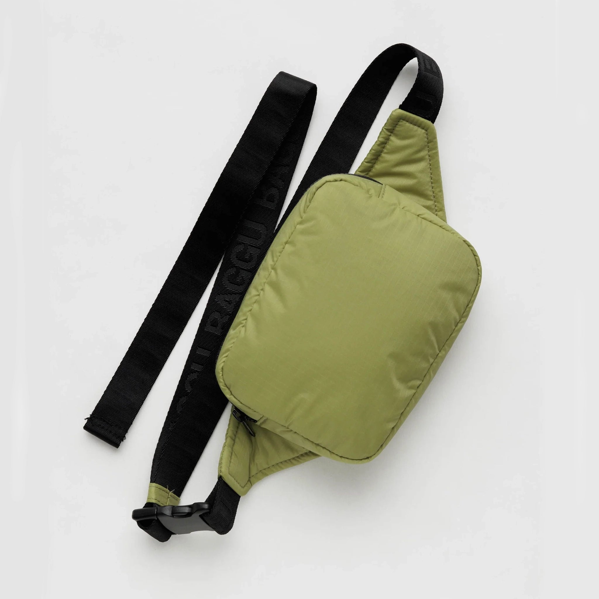 On a white background is the puffy fanny pack in the shade pistachio, which is an olive green color with a black adjustable strap that has subtle letters that read, "BAGGU" in all caps. 