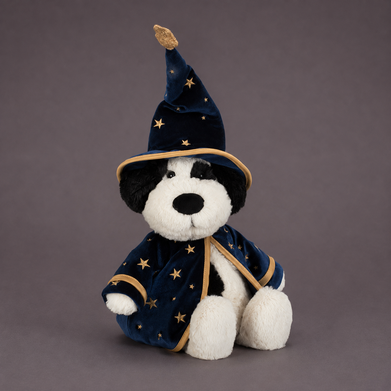 A black and white puppy shaped plush toy wearing a wizard costume. 