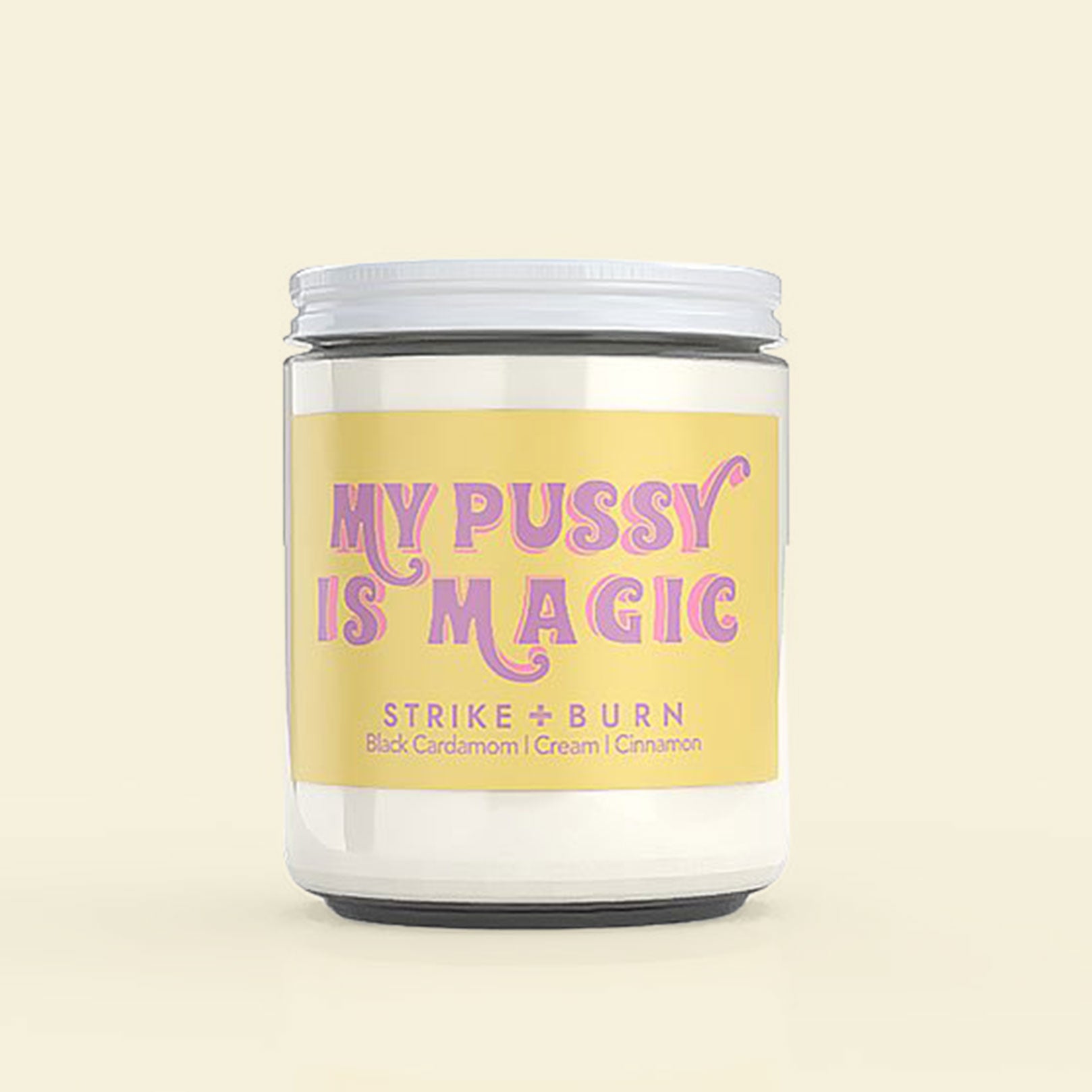 A glass jar candle with a yellow label and purple font that reads, "My Pussy is Magic."