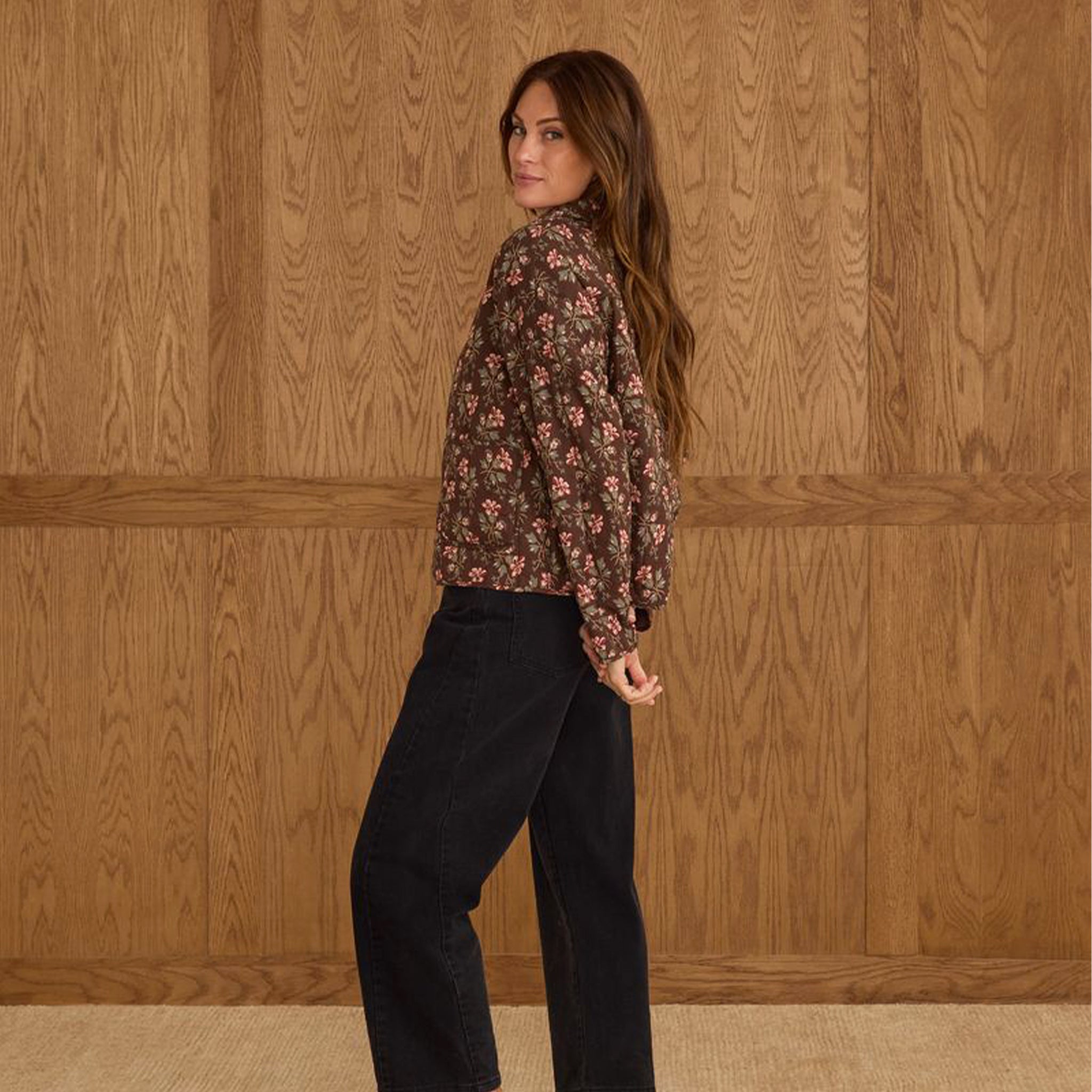 A brown quilted jacket with a pink and ivory floral print. 