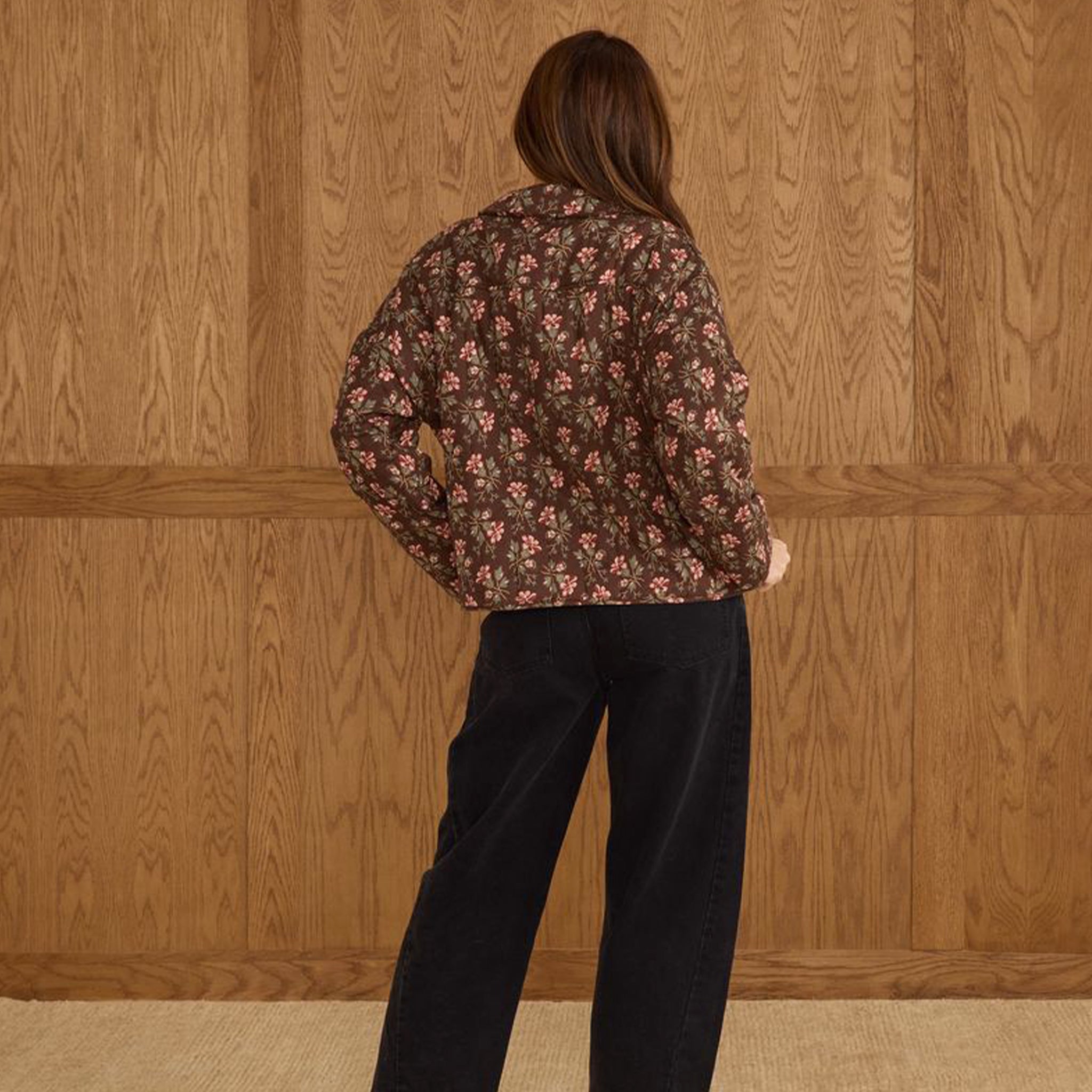 A brown quilted jacket with a pink and ivory floral print. 