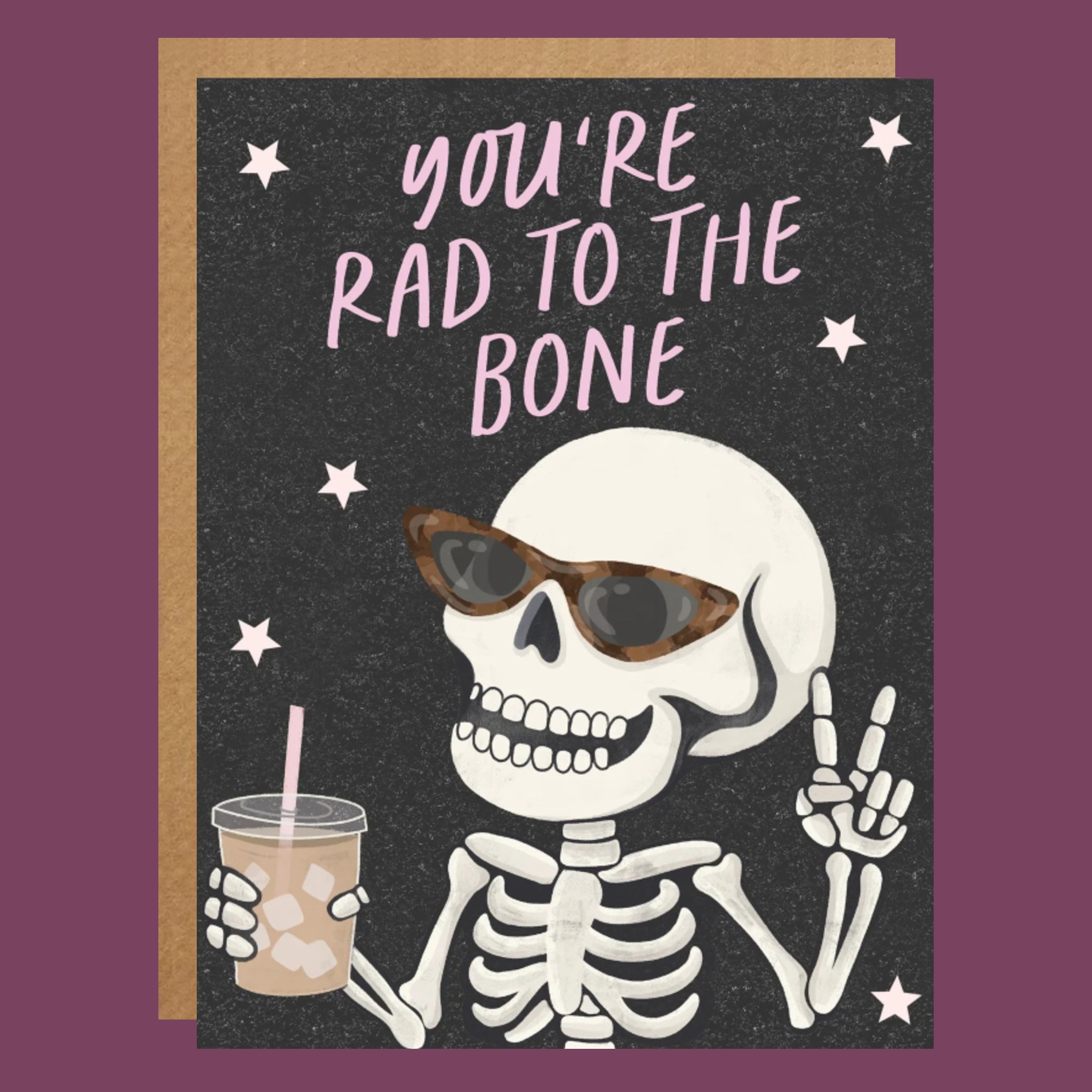 A black card with a skeleton graphic holding an iced coffee and wearing sunglasses along with text above that reads, 'You're Rad To The Bone'. 