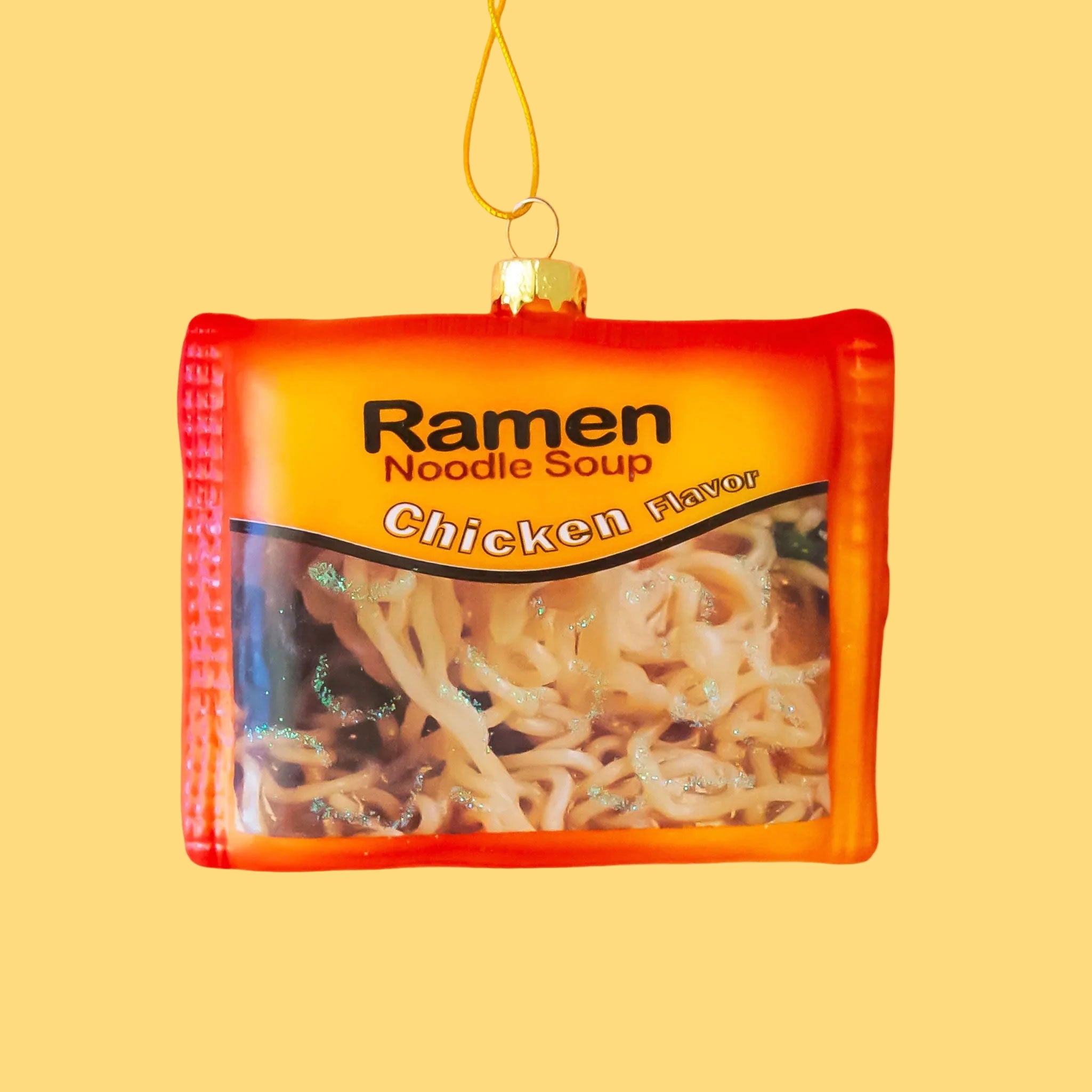 An orange ramen package shaped ornament with text that reads, 'Ramen Noodle Soup Chicken'.