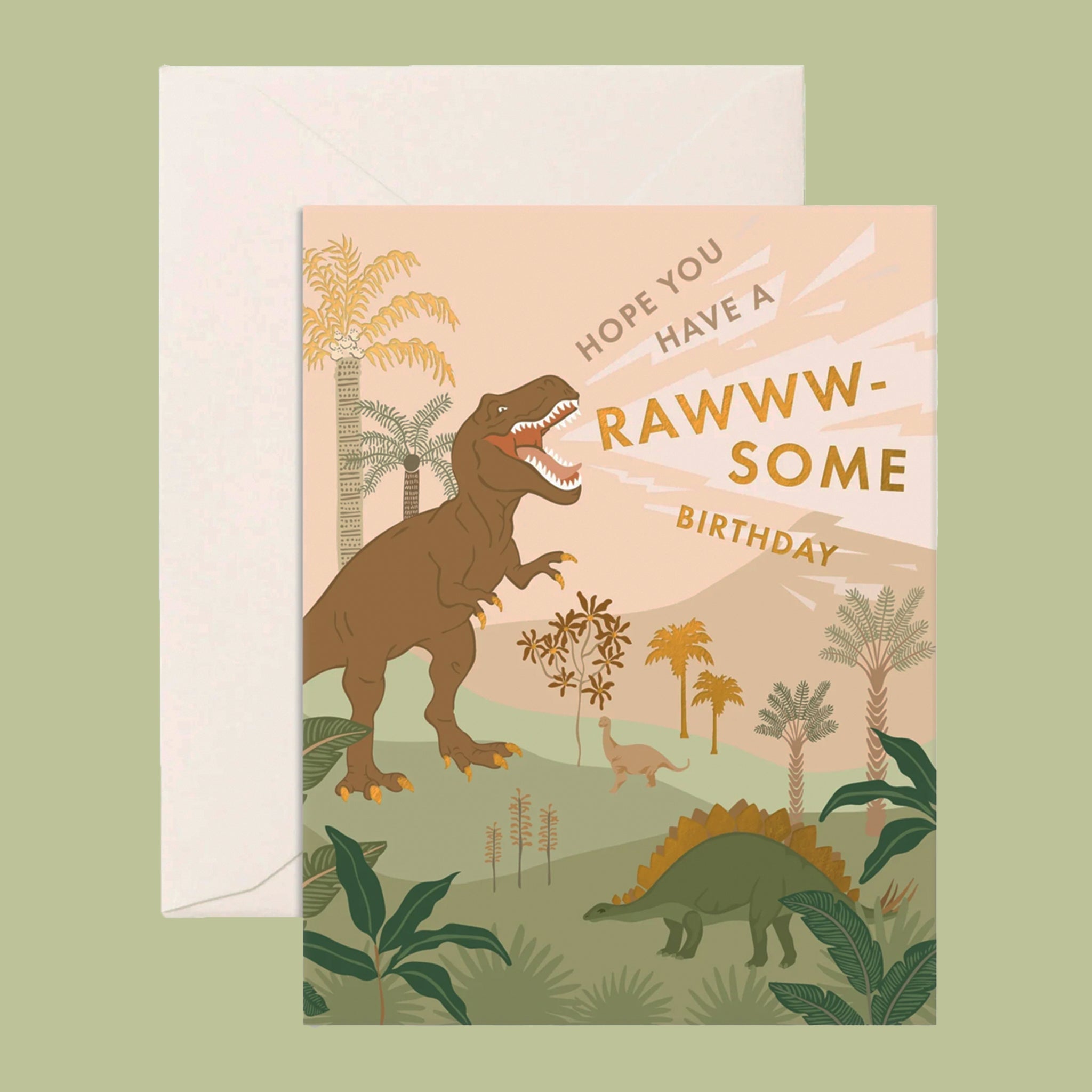 On a green background is a birthday card with a graphic of dinosaurs in a tropical landscape with gold foiled text that reads, "Hope You Have A Rawww-Some Birthday".