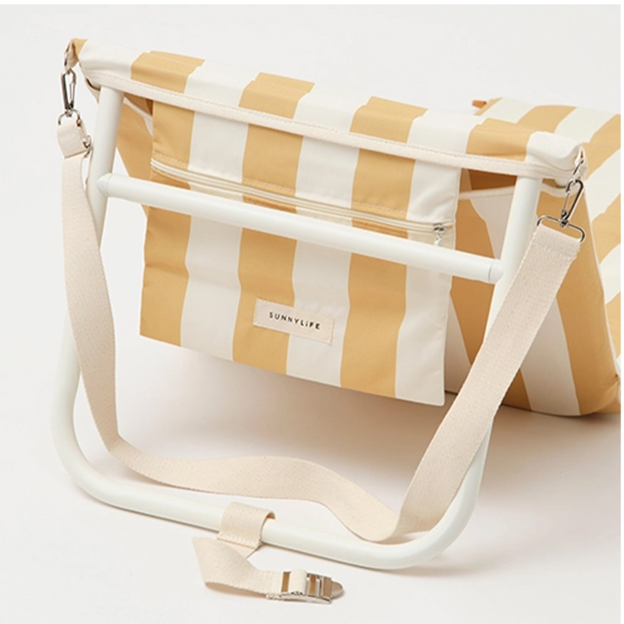 A mustard and ivory striped unfoldable beach or pool chair with folds into a compact square with a strap for carrying.