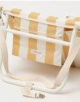 A mustard and ivory striped unfoldable beach or pool chair with folds into a compact square with a strap for carrying.
