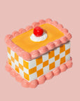 An orange and pink vintage cake shaped storage box made out of ceramic. 
