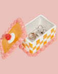 An orange and pink vintage cake shaped storage box made out of ceramic. 