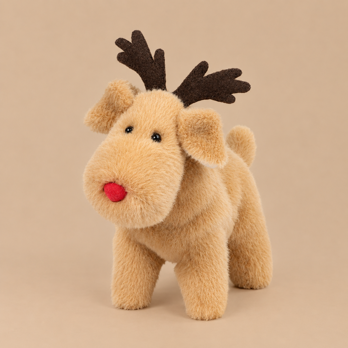 a tan reindeer shaped stuffed animal with a red nose.