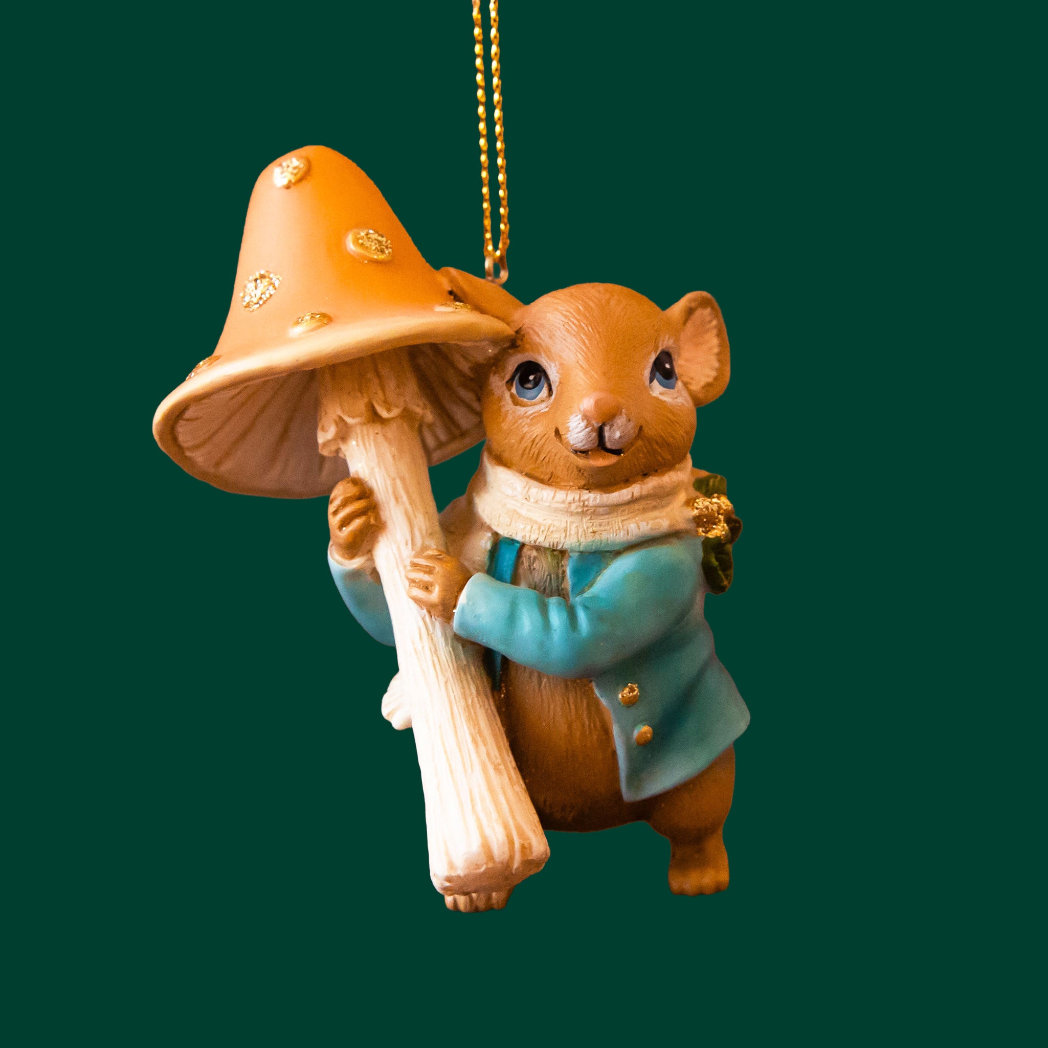 A mouse shaped ornament holding an orange mushroom. 
