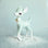 On a light blue background is a mint green retro deer figurine with white spot details and a gold bell at the front of its neck and staged on top of fake snow.