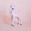 On a light pink background is a cool pink retro deer figurine with white spots and details, a sweet expression and a gold bell on the front of their neck.